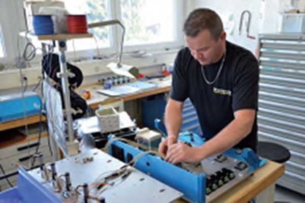 Monteur UNIMEC assemblant un équipement bleu à l'établi